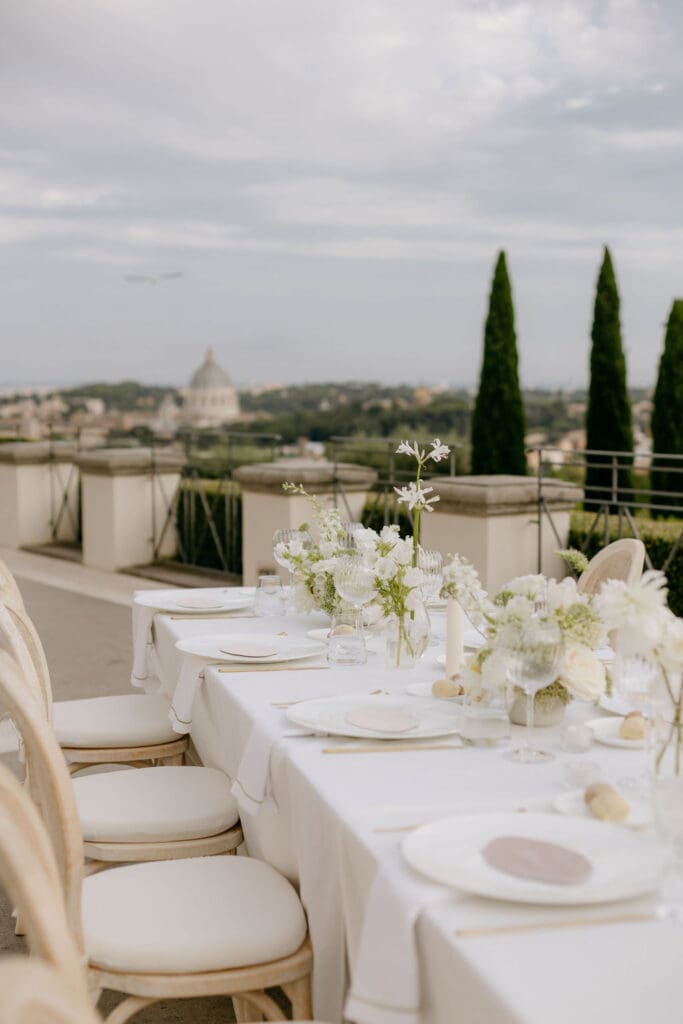 A photo taken at a Villa Miani wedding reception depicts an elegant tablescape with neutral linens & florals 
