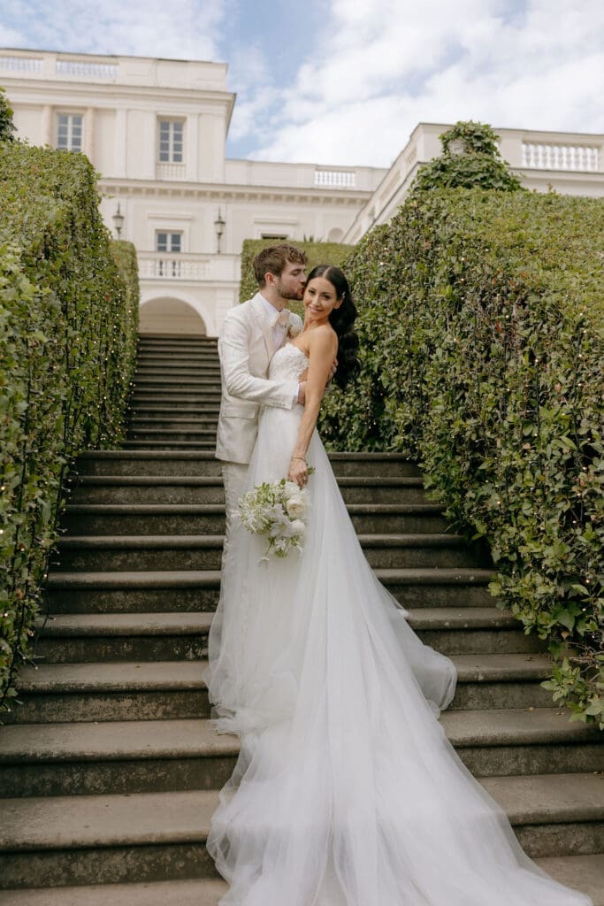 Newlyweds embrace for a bridal portrait taken on the stairs at their villa miani rome wedding