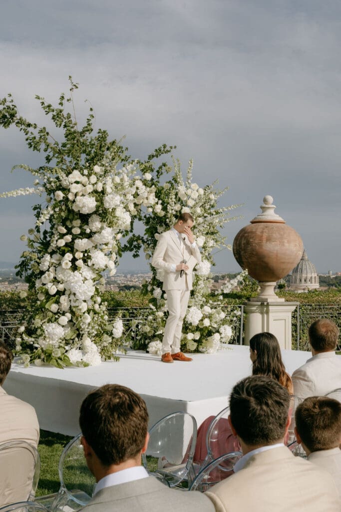 A groom wipes away tears before a spray of florals at his villa miani rome wedding